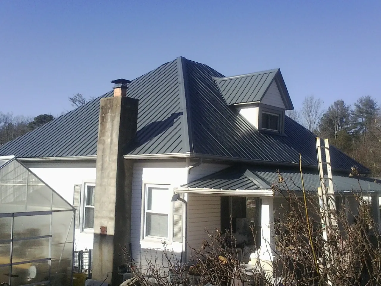 Dark blue standing seam metal roof on a white farmhouse with dormer — Slate & Tile Roof Repair by Roofing Brothers in Manteno