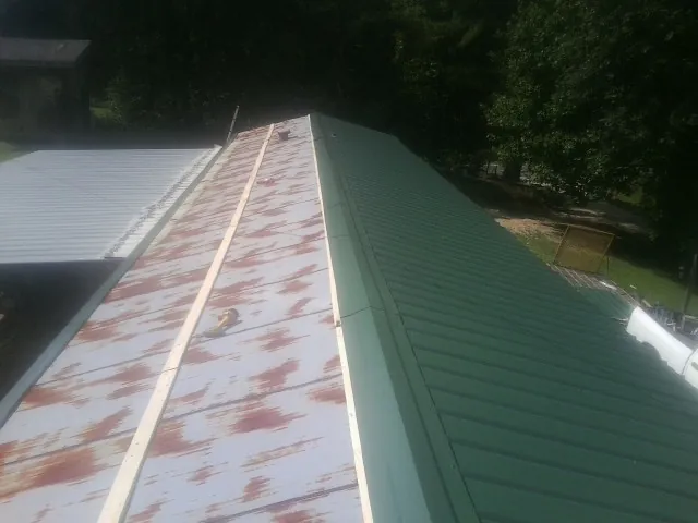 Old rusted panels beside newly installed green metal roofing — Wind Damage Roof Repair by Roofing Brothers in Manteno