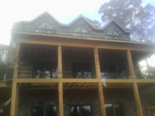 Dormers and porch framing on a large log home under construction — Roof Coating work by our crew in Manteno