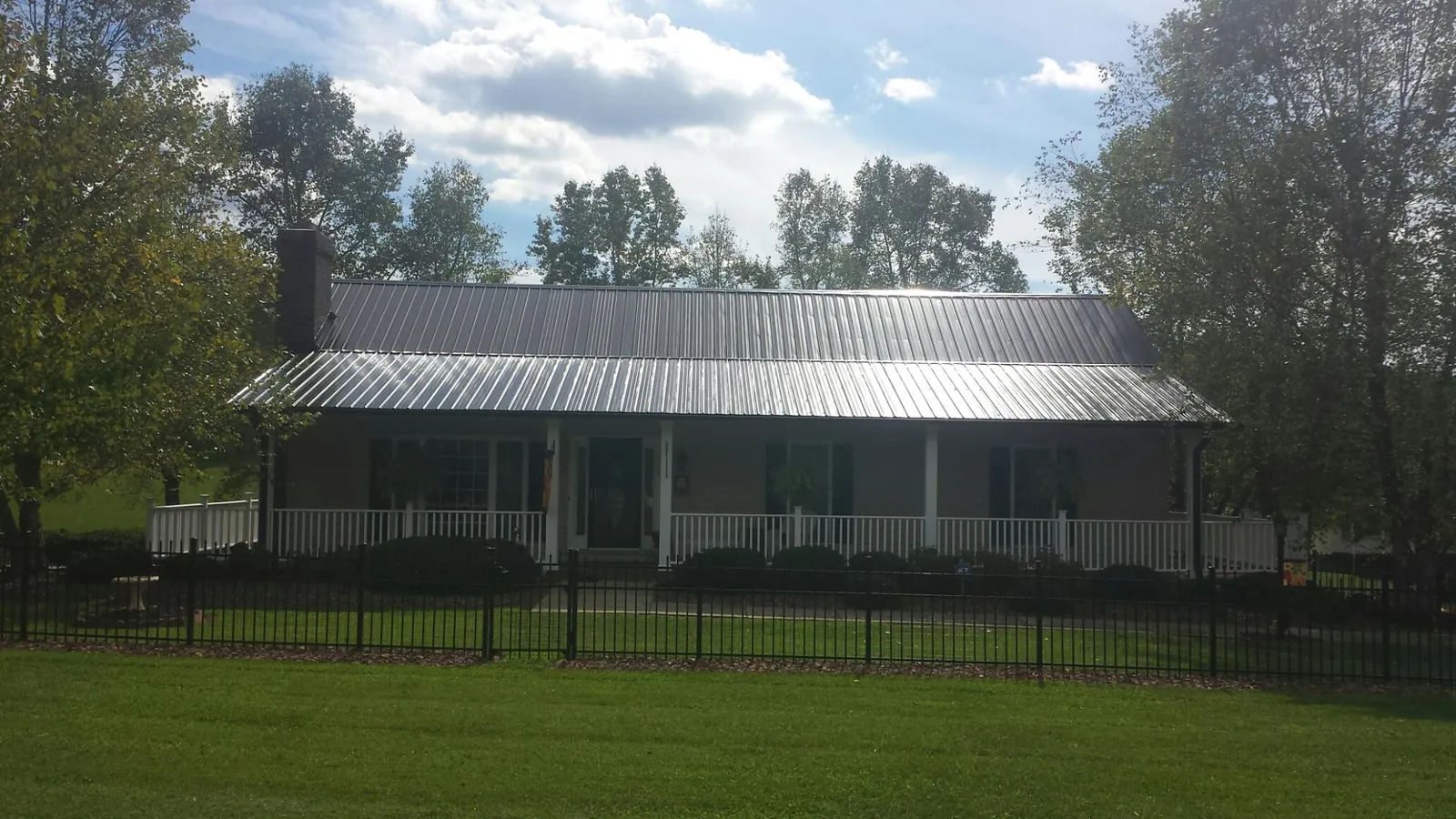 Gray metal roof on a brick ranch with a full width front porch — Gutter Guard Installation work by our crew in Manteno