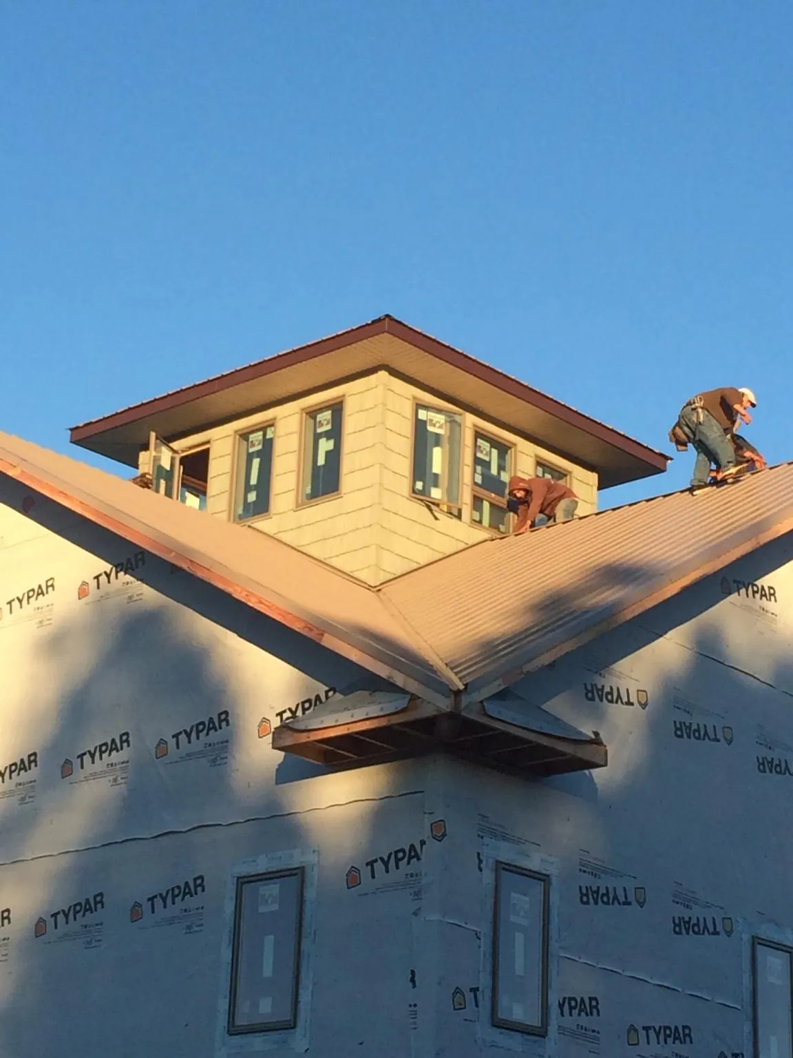Roofers working around a rooftop cupola on a new metal roof at sunset — Roof Waterproofing in Manteno by Roofing Brothers